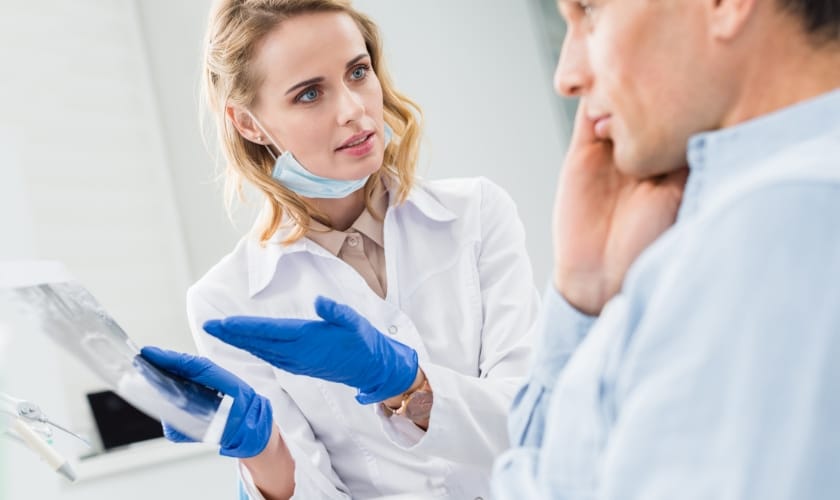 Dentist holding a x ray plate and discussing with patient