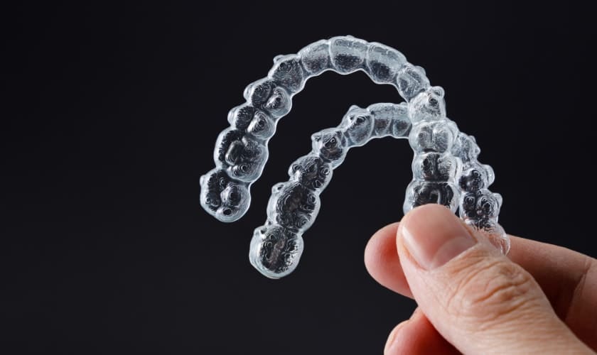 Hand holding clear aligner
