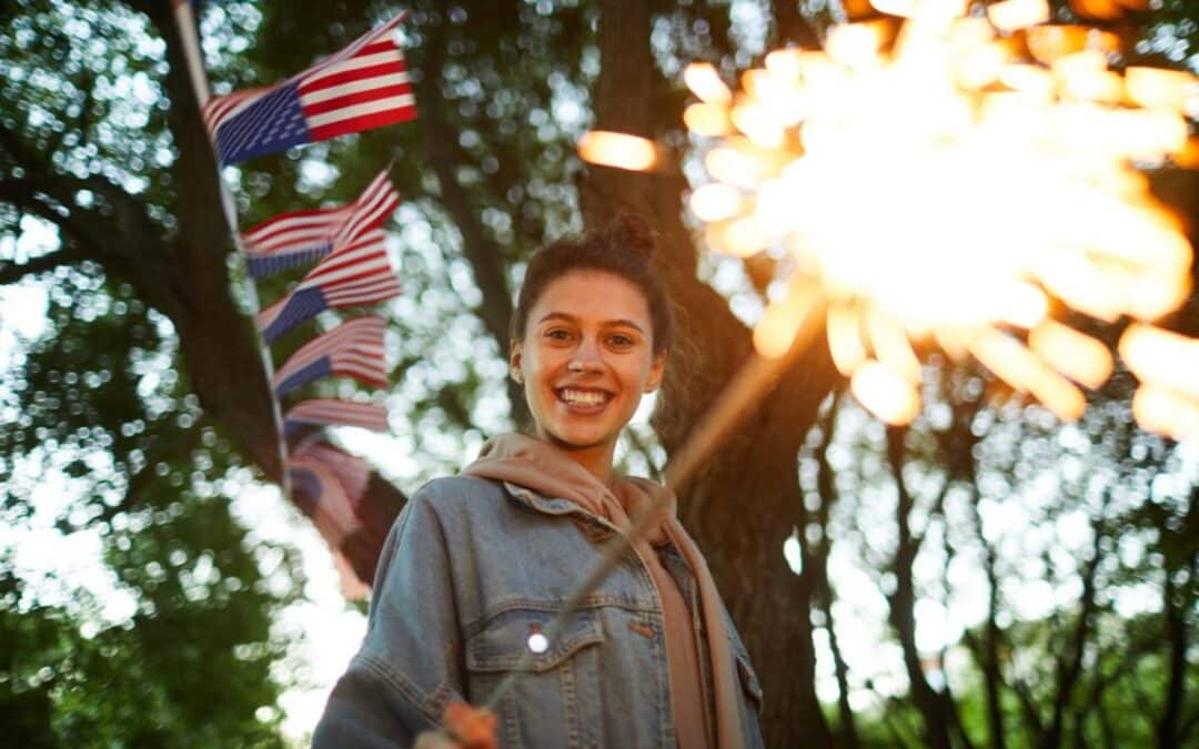Woman holding american flags smiling outdoors with sparklers