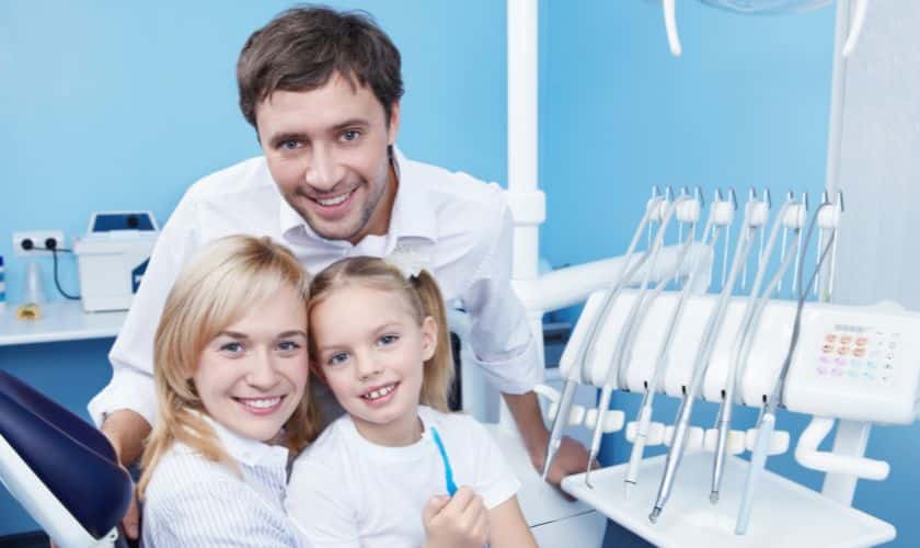 Dentist with family in dental chair smiling
