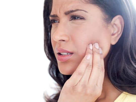 Woman touching her cheek in discomfort
