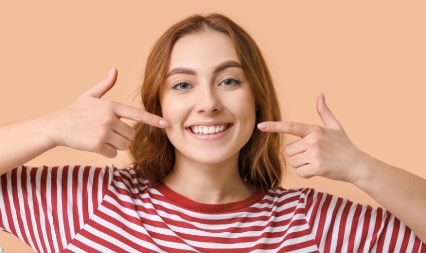 Woman pointing to her smiling teeth