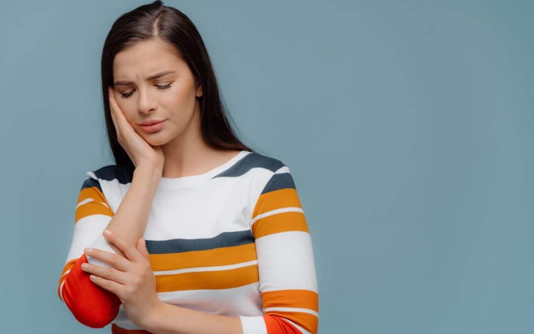 Woman touching her cheek in discomfort