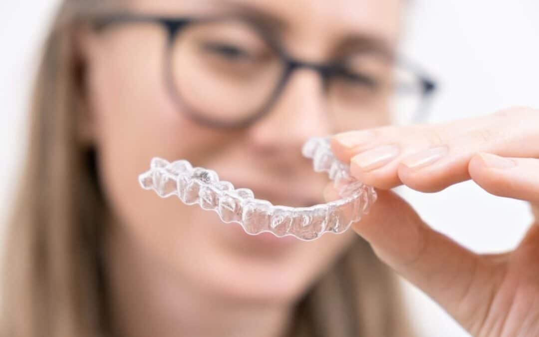 Woman holding clear aligner smiling