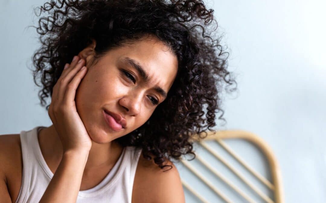 Woman with curly hair touching her cheek